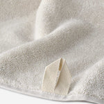 Close-up of a cream cotton towel highlighting the soft terry texture and woven border detail.