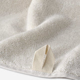 Close-up of a cream cotton towel highlighting the soft terry texture and woven border detail.