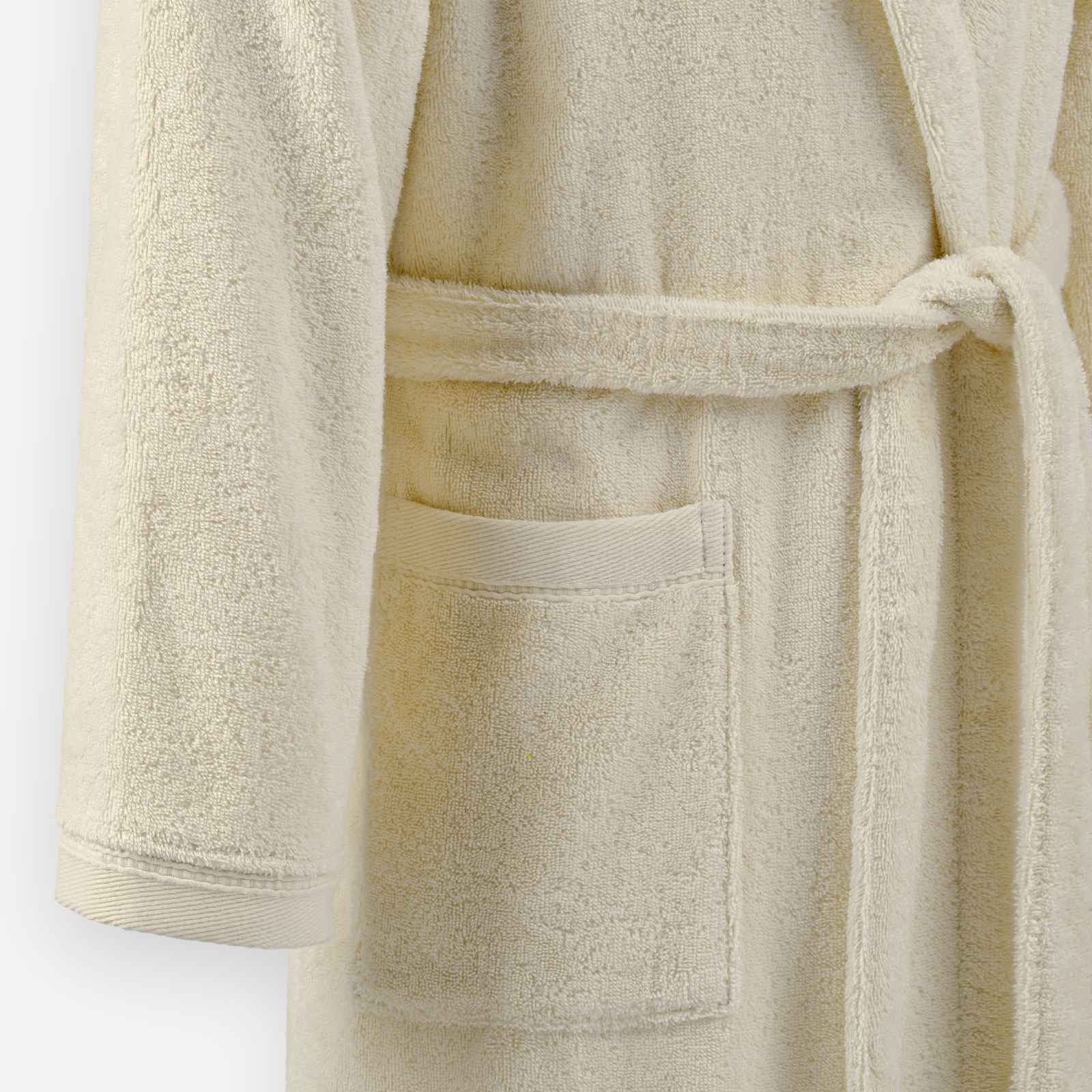 Close-up of a cream terry cloth bathrobe showing the tie belt and front pocket detail.