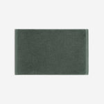 Dark green cotton bath sheet in horizontal orientation with woven border bands, shown against a white background.