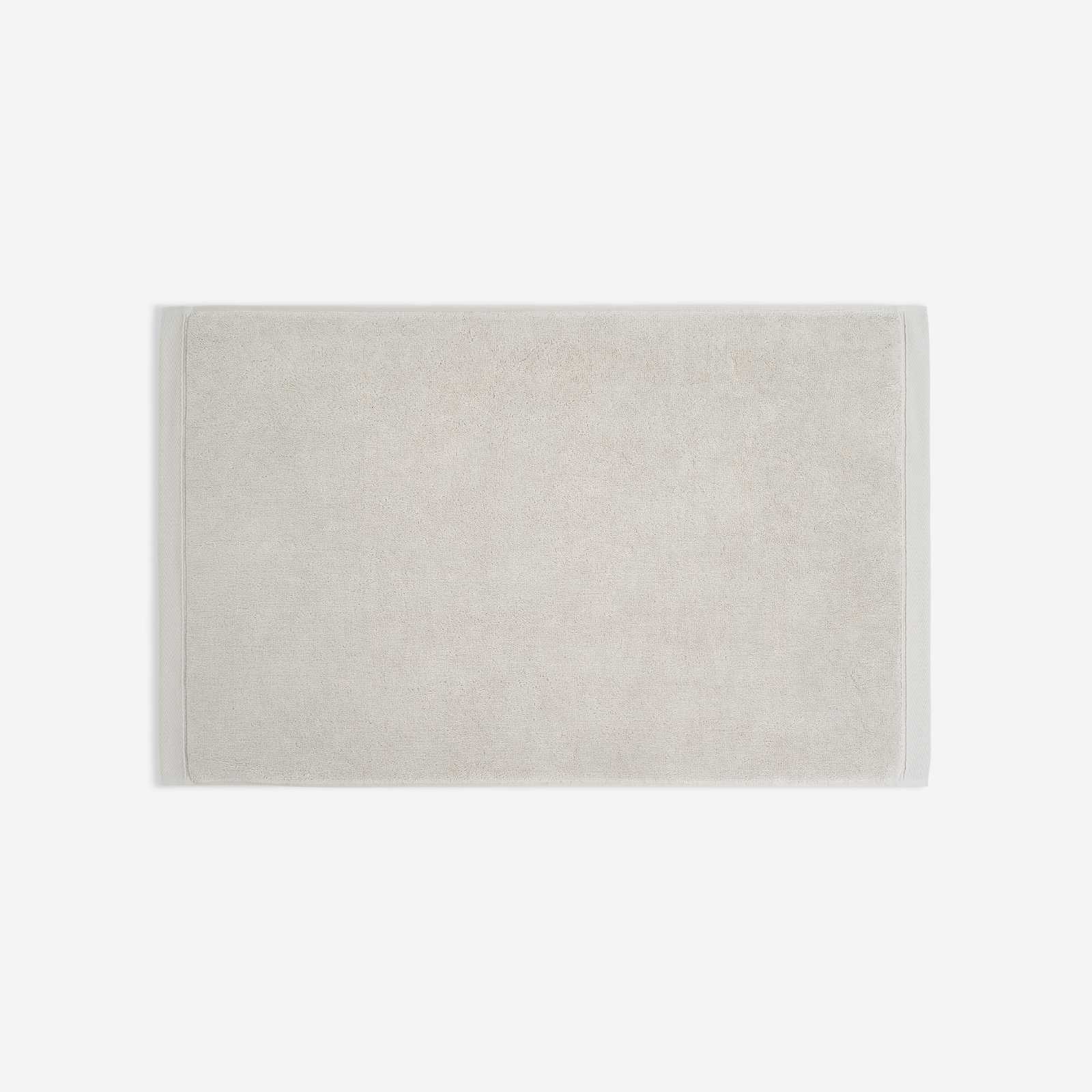 Light beige cotton bath sheet in horizontal orientation with woven border bands, shown against a white background.