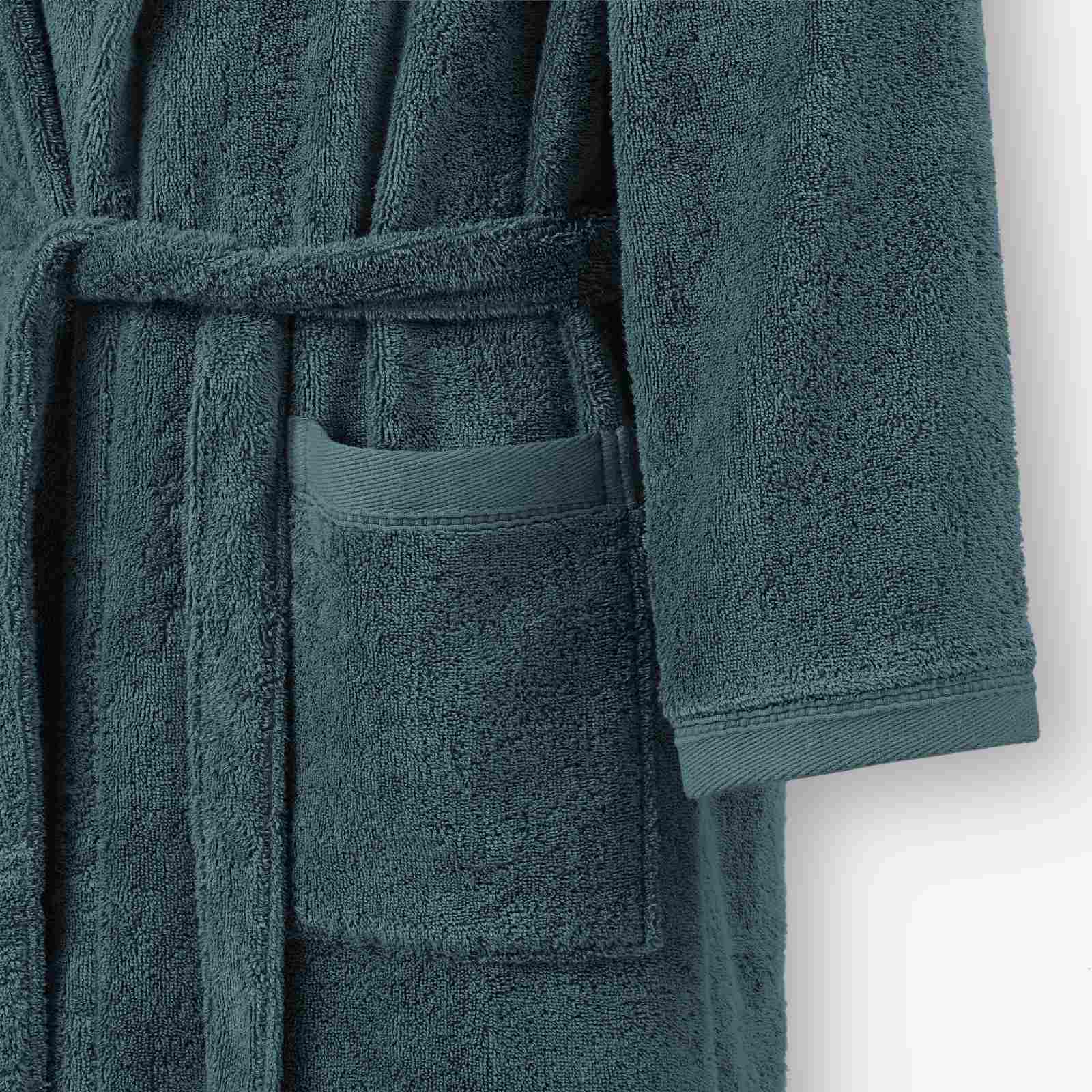 Close-up of a teal terry cotton bathrobe showing the waist tie belt, front patch pocket, and sleeve cuff detail.