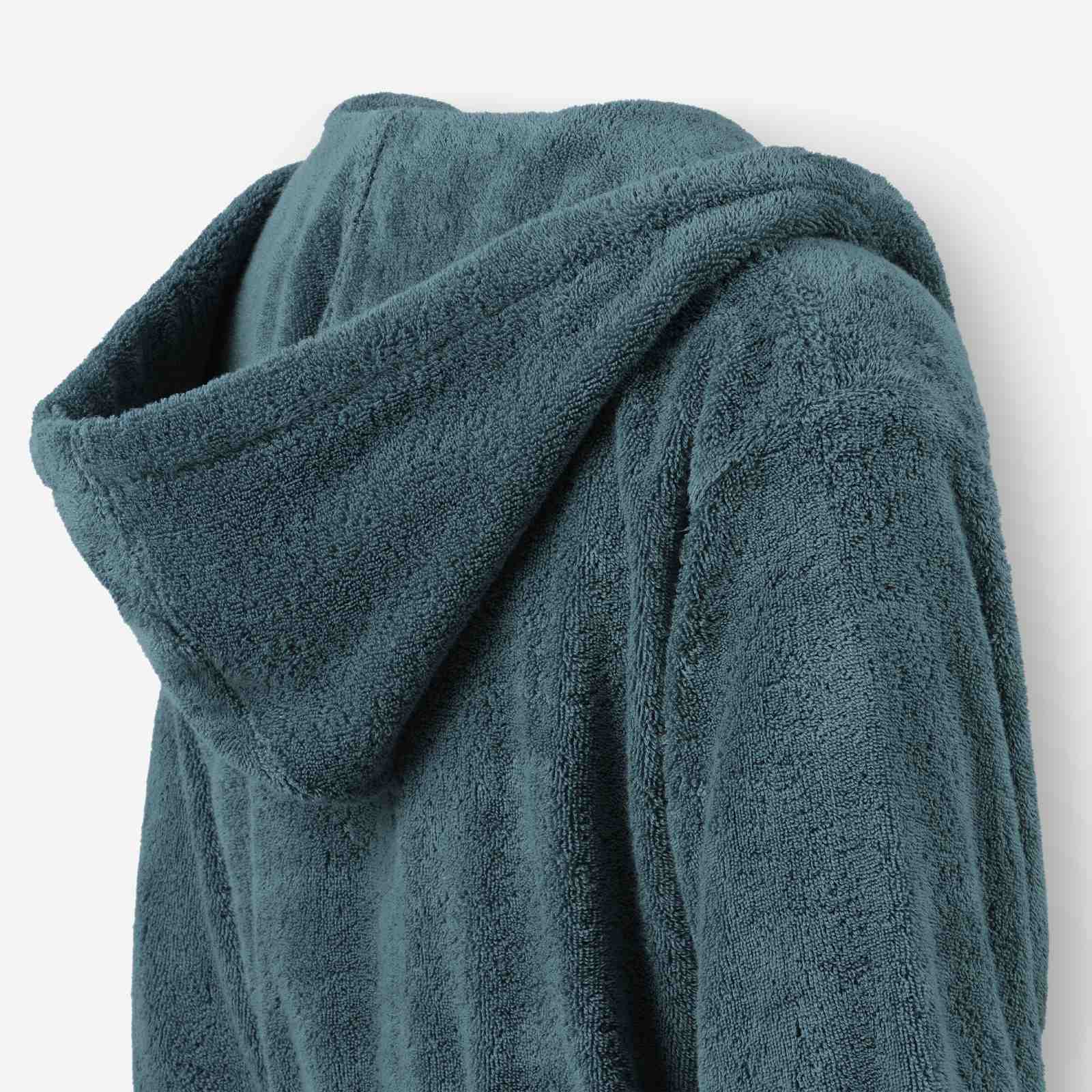 Close-up of a teal terry cotton bathrobe showing the hood detail and plush texture.