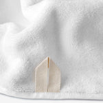 Close-up of a white cotton bath sheet highlighting the terry texture and integrated beige hanging loop.