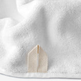 Close-up of a white cotton bath sheet highlighting the terry texture and integrated beige hanging loop.