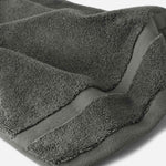 Close-up of a charcoal gray cotton bath sheet highlighting the soft terry texture and woven border detail.
