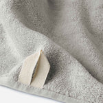 Close-up of a light gray cotton bath sheet highlighting the terry texture and integrated hanging loop detail.