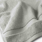 Close-up of a light gray cotton bath sheet highlighting the dense terry texture and woven border detail.