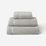 Stack of three light gray cotton towels in different sizes, shown against a white background.