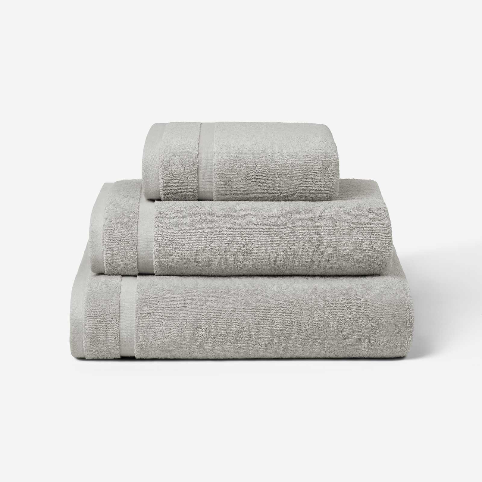 Stack of three light gray cotton towels in different sizes, shown against a white background.