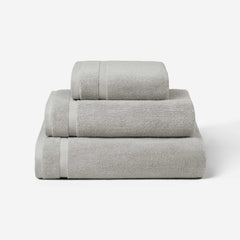 Stack of three light gray cotton towels in different sizes, shown against a white background.