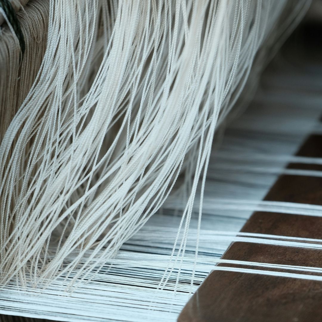 Close-up of white cotton yarn threads on a traditional textile loom.