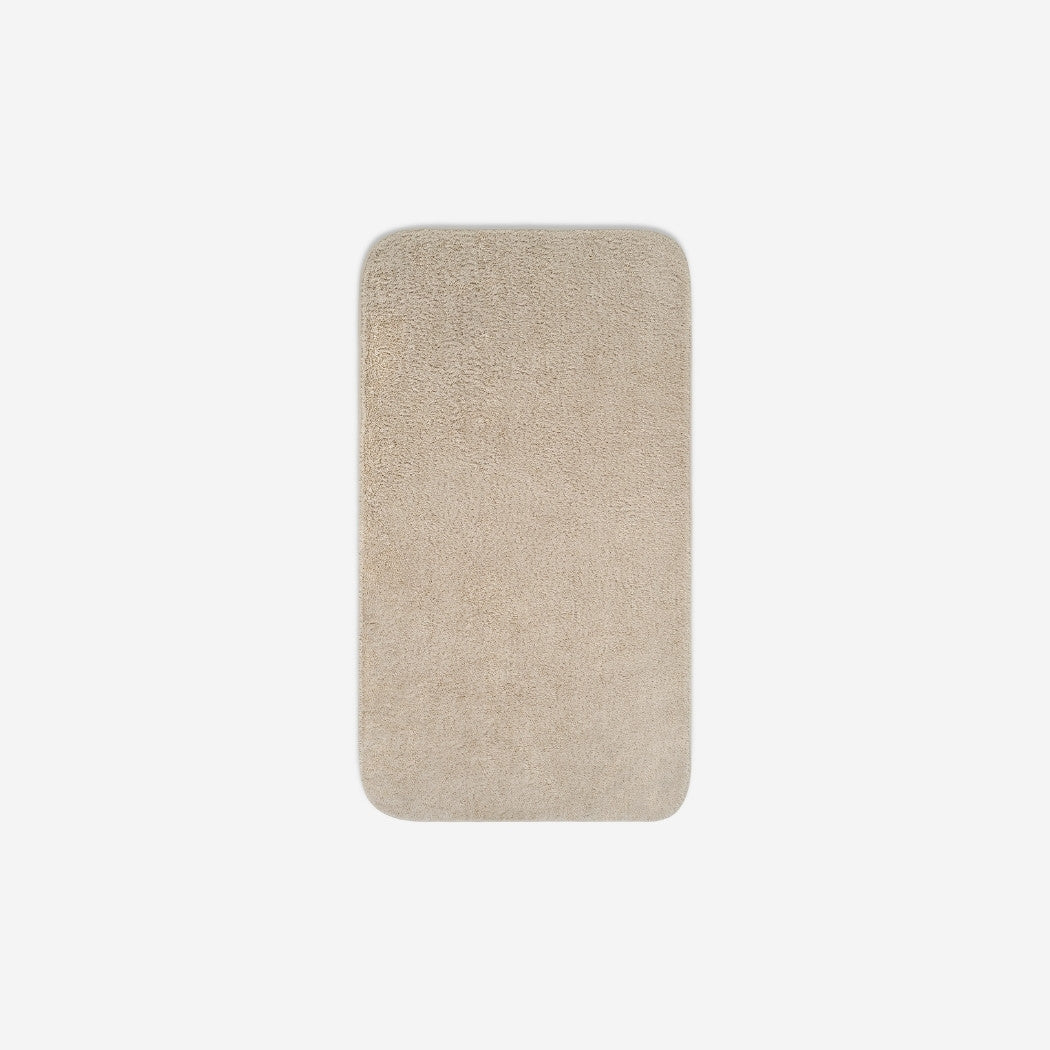 Top view of a light cream organic cotton face towel with rounded corners, displayed flat on a white background.