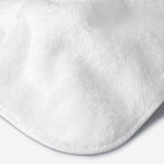 Close-up of a white cotton towel highlighting the soft terry texture, rounded corner finish, and subtle embroidered logo detail.