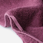 Close-up of a cotton towel showing dense plush pile, reinforced edge binding, and an integrated hanging loop.