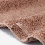 Close-up detail of a dusty rose cotton towel featuring soft plush pile, reinforced edge binding, and a practical hanging loop.