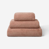 Stack of three dusty rose luxury cotton towels in different sizes, featuring a plush soft texture against a neutral background.