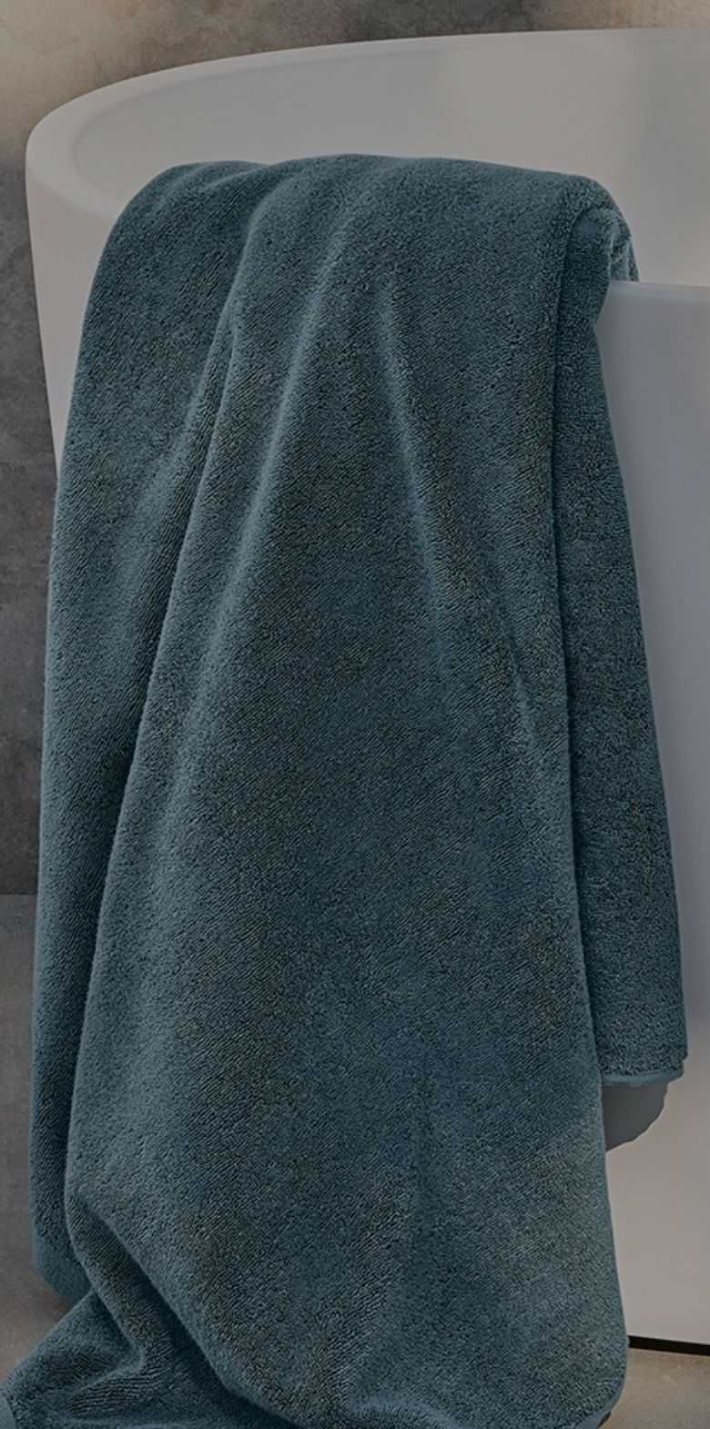 Teal bath towel draped over a white bathtub