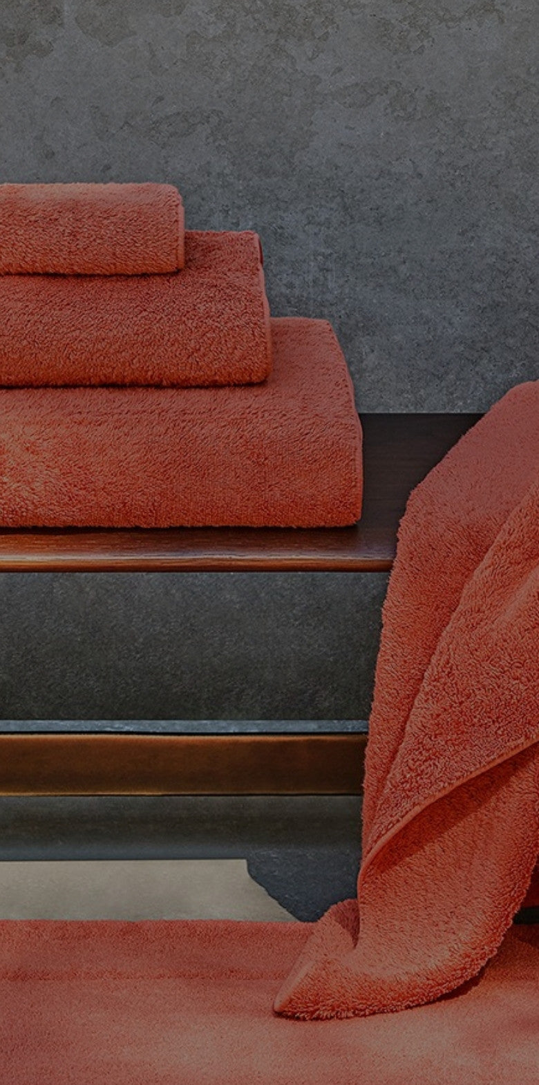 Terracotta bath towels stacked and draped over a chair