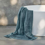 Teal towel draped over a white bathtub in a bathroom setting