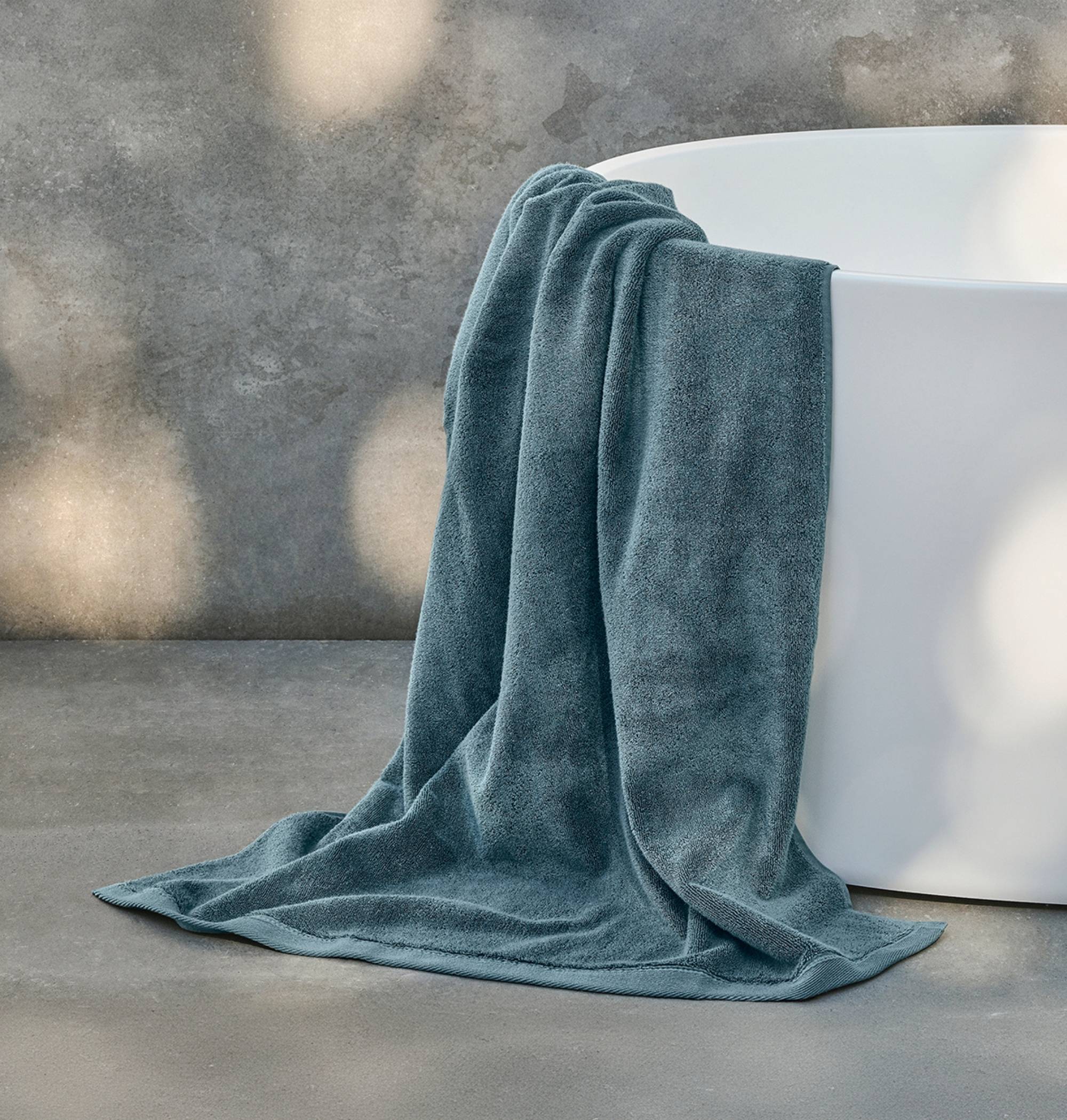Blue towel draped over a white bathtub in a bathroom setting