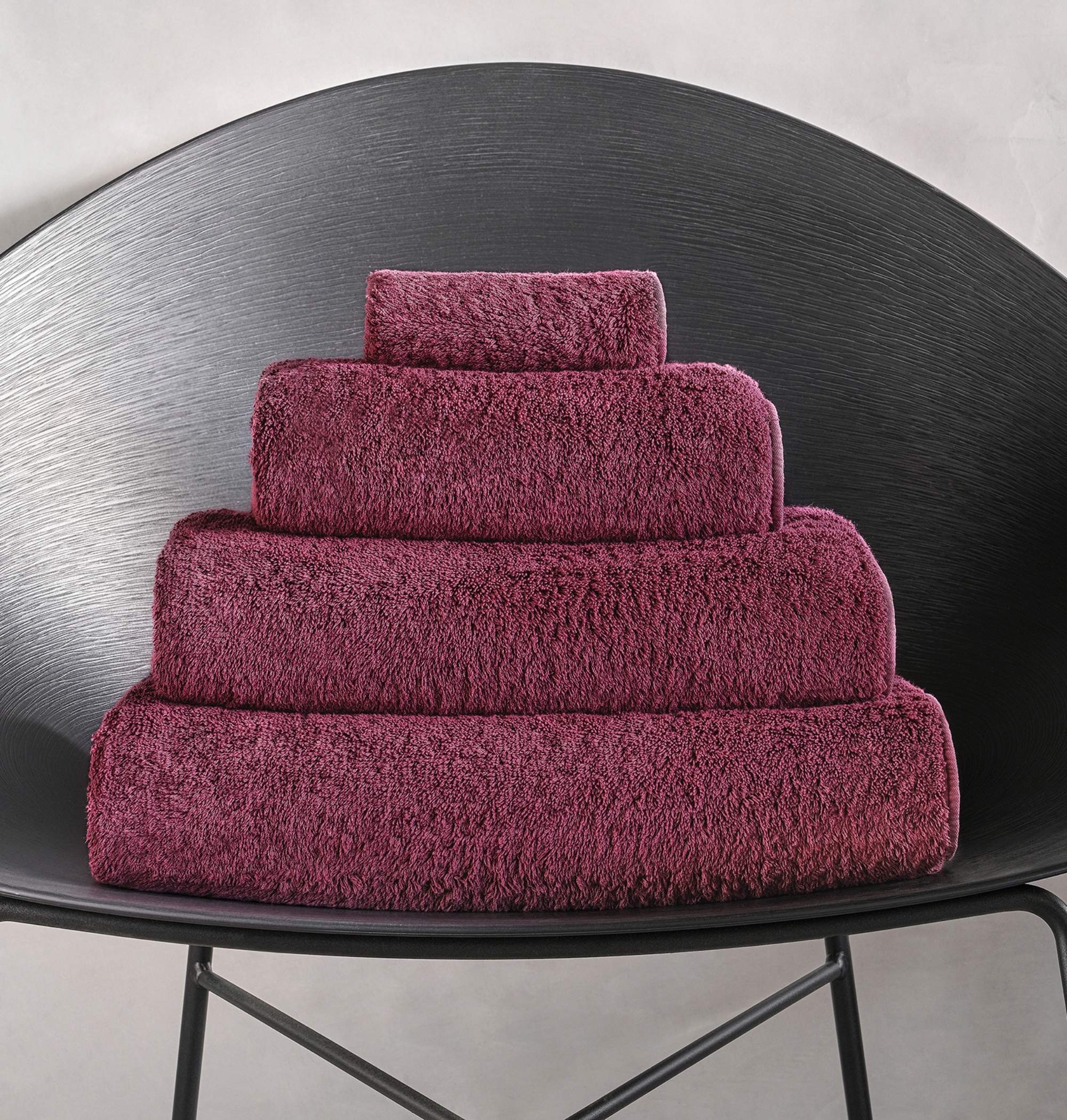 Stack of purple towels on a black chair against a gray background