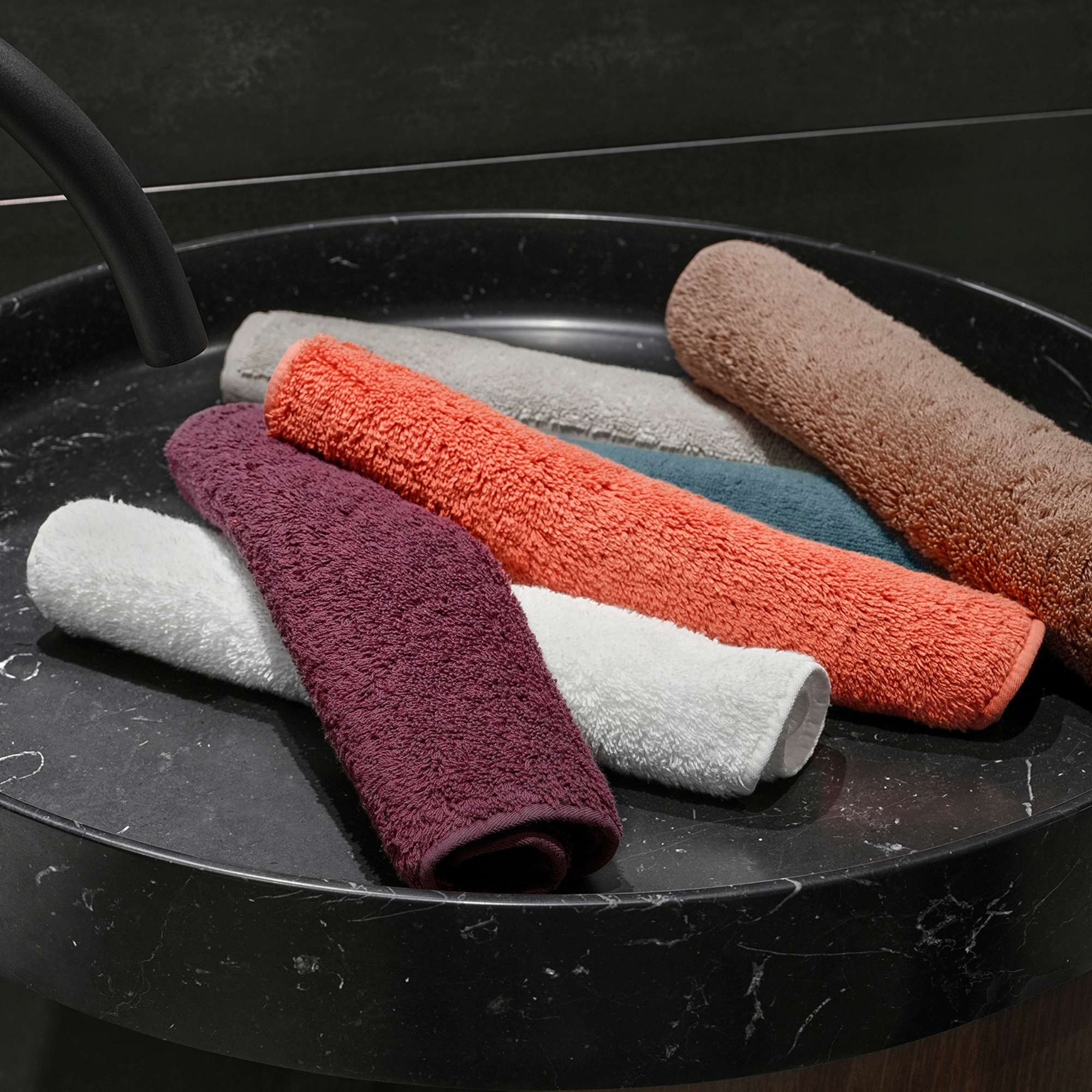 Set of colorful rolled-up towels on a dark surface