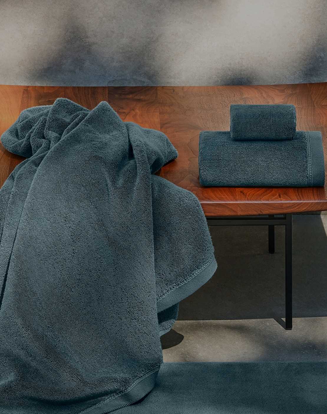 Teal towels on a wooden bench with a textured wall background