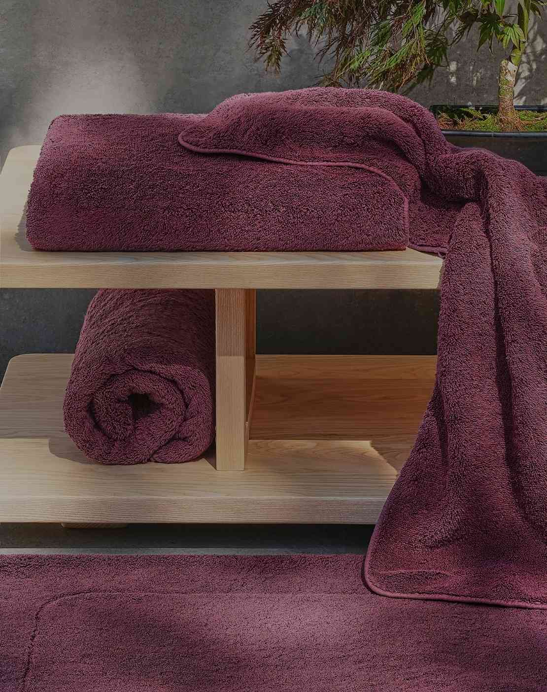 Purple towels on a wooden shelf with a neutral background