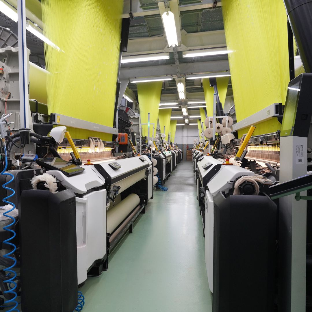 Textile production line with large yellow fabric rolls in a factory setting