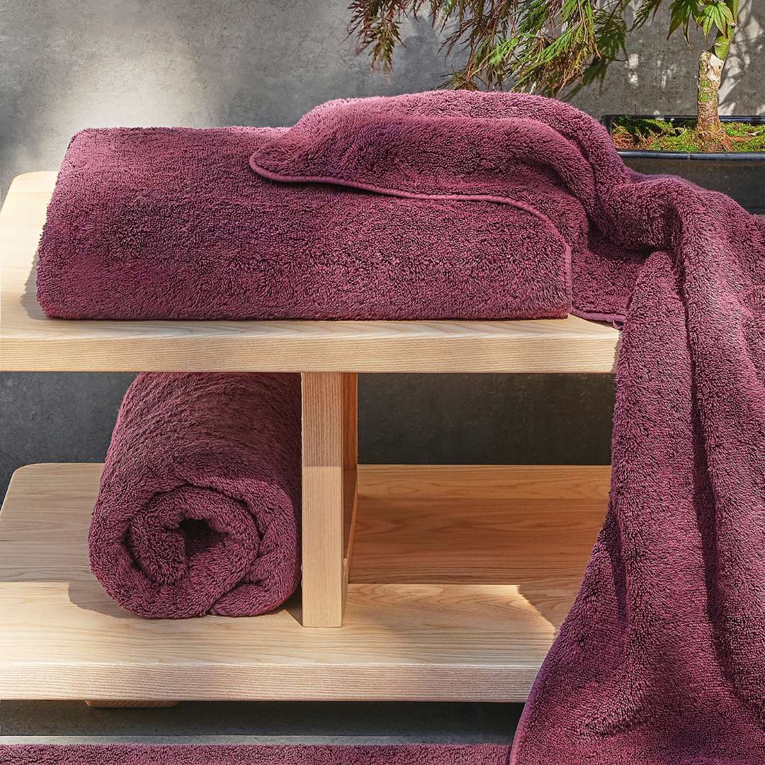 Purple towels on a wooden shelf with a neutral background.