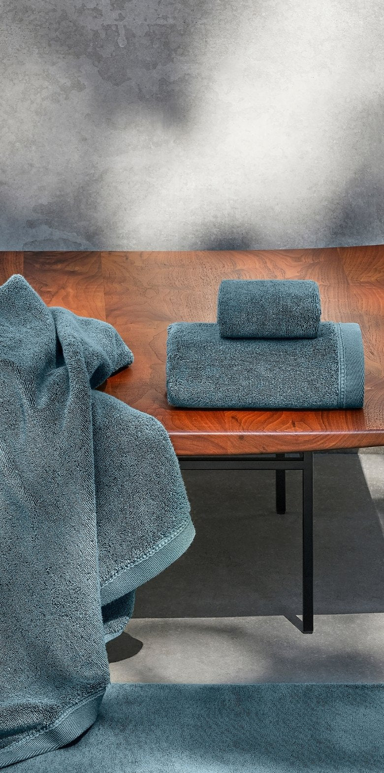 Blue towel on a wooden table with a textured gray wall in the background.