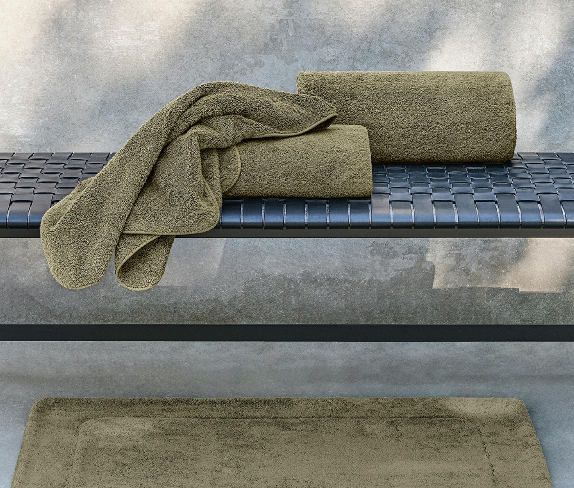 Green bath towels on a metal surface with a concrete wall background