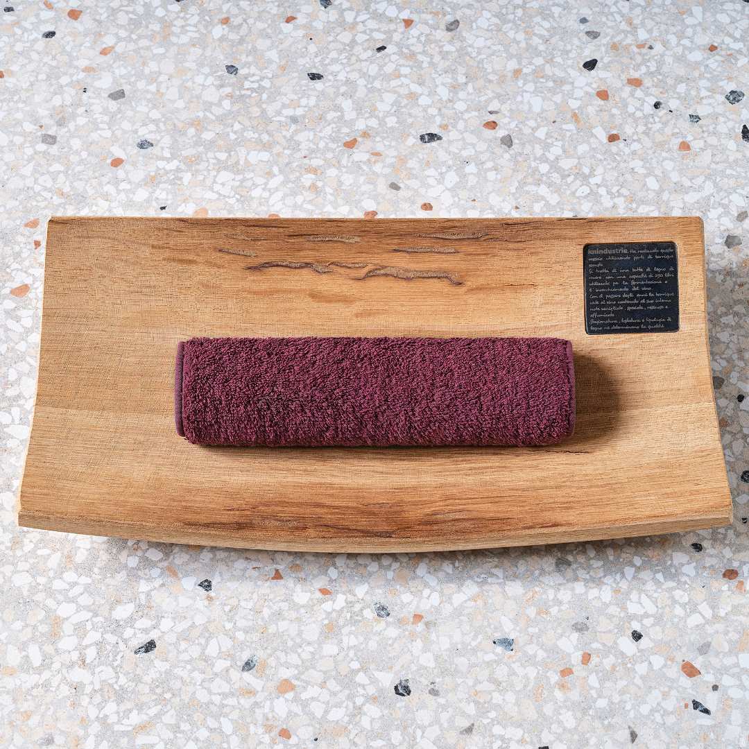 Purple washcloth rolled on a wooden tray