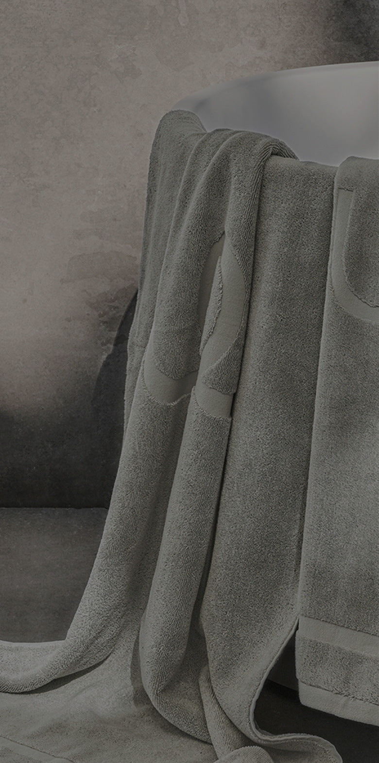 Grey bath towels draped over a white bathtub