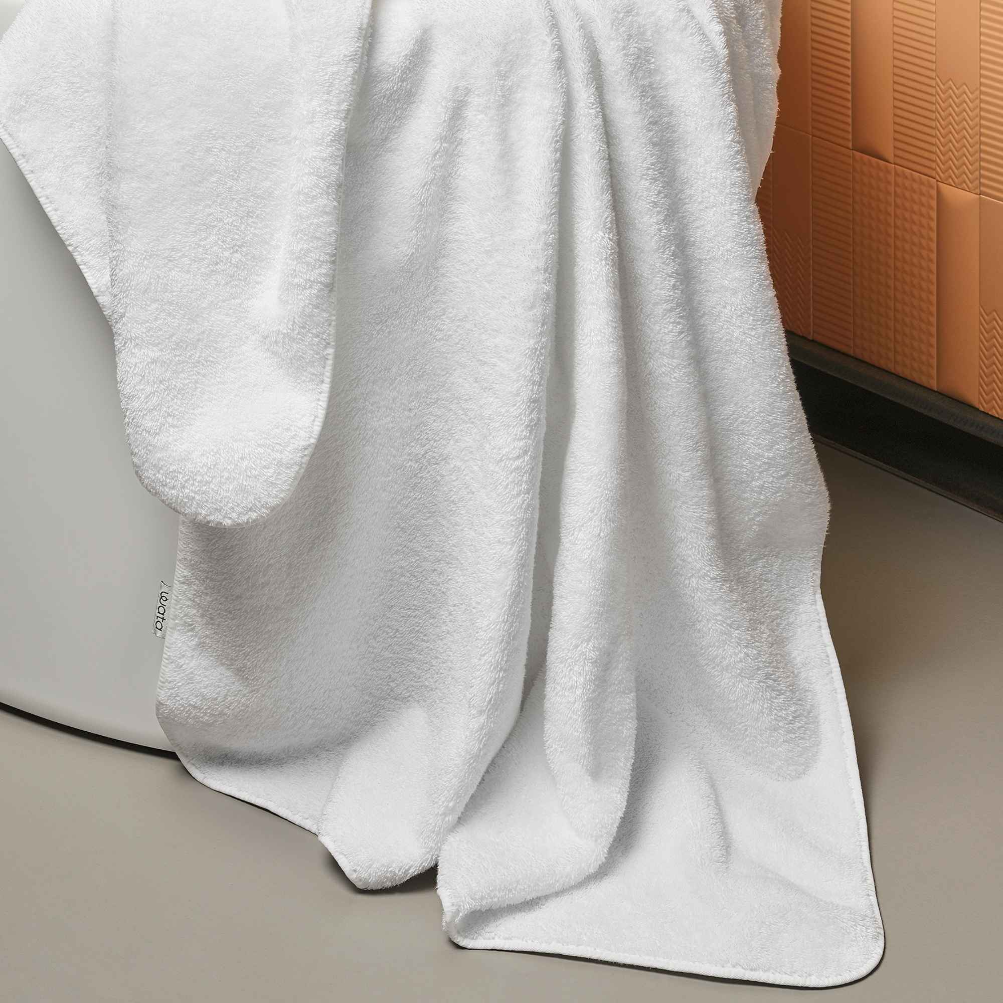 White towel draped over a bathtub with an orange cushioned backrest.