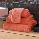 Stack of orange towels on a wooden surface with a tiled wall background