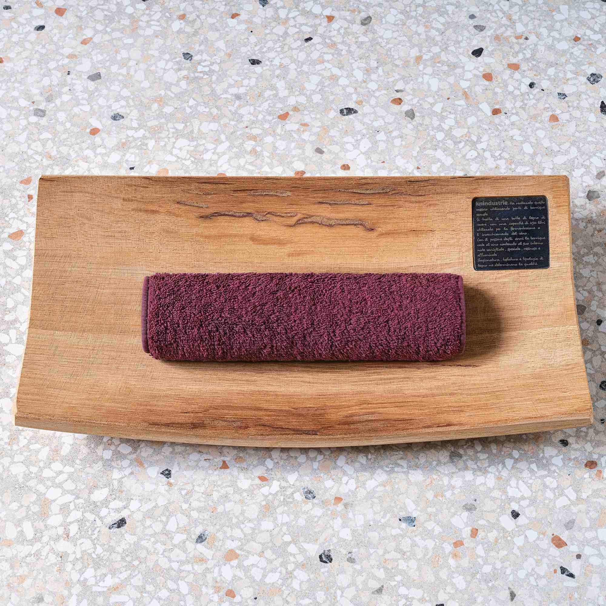 A wooden block with a purple washcloth wrapped around it on a speckled countertop.