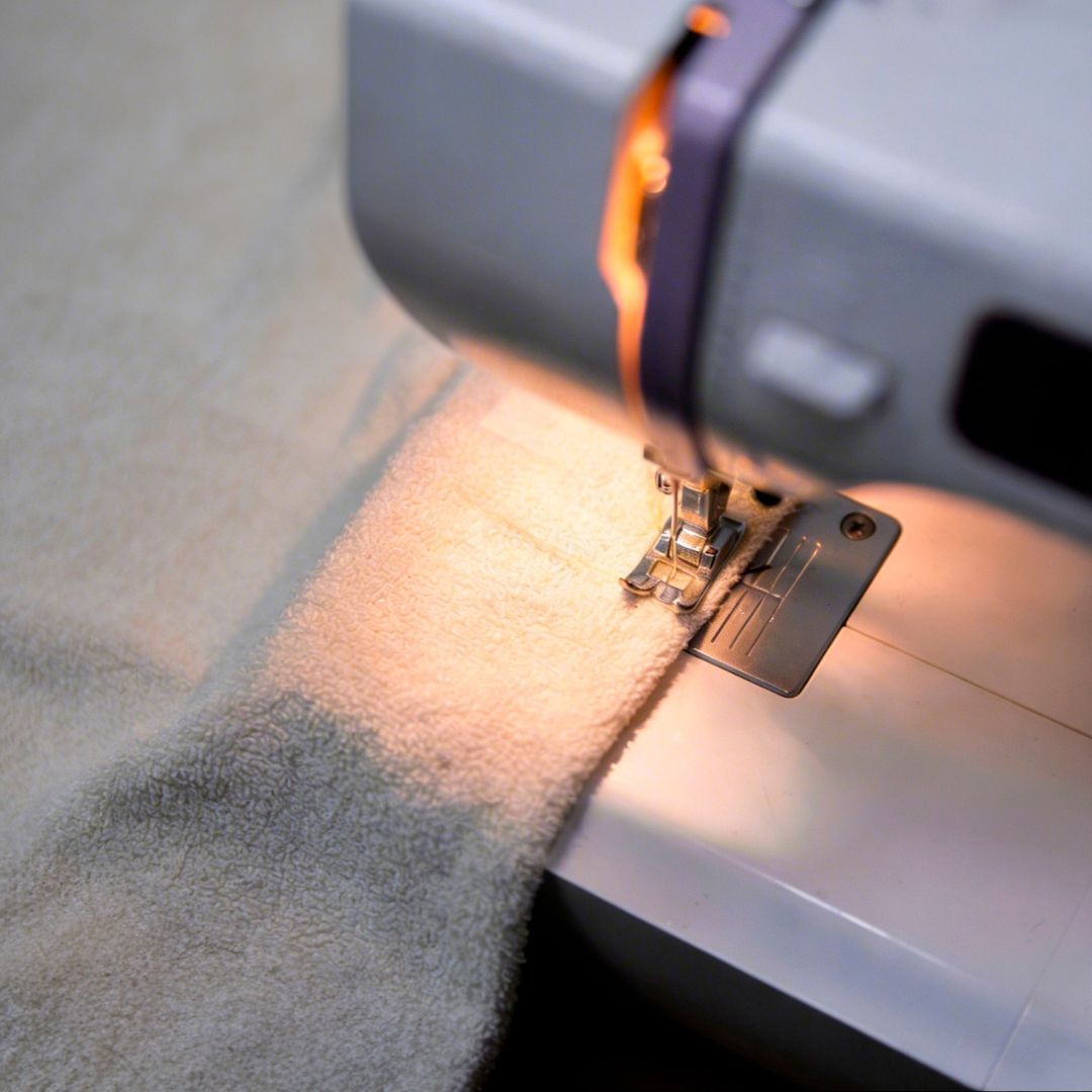 Close-up of a sewing machine needle stitching fabric.